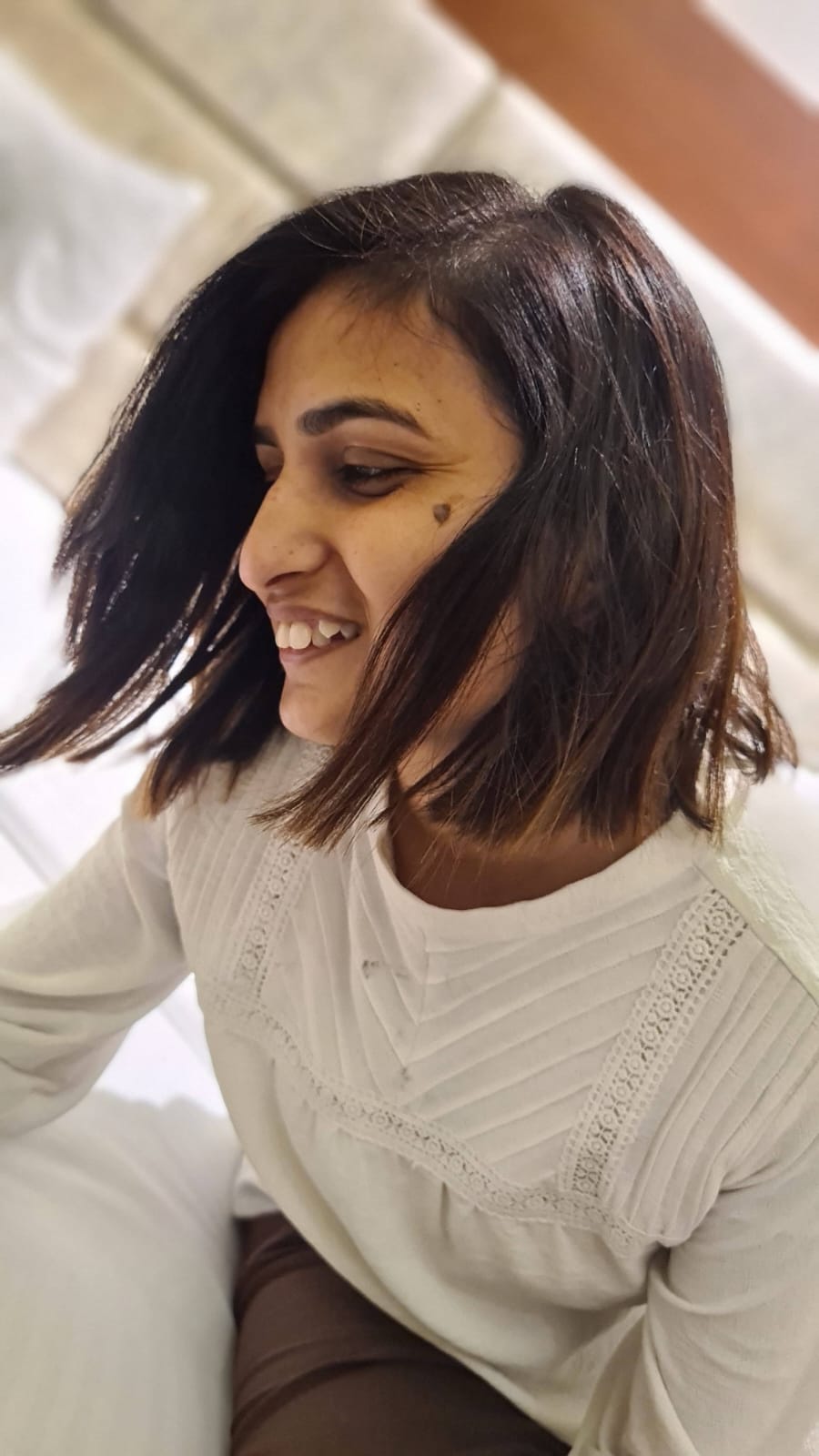Candid joy — white lace top, hair mid-flip, unguarded laughter indoors