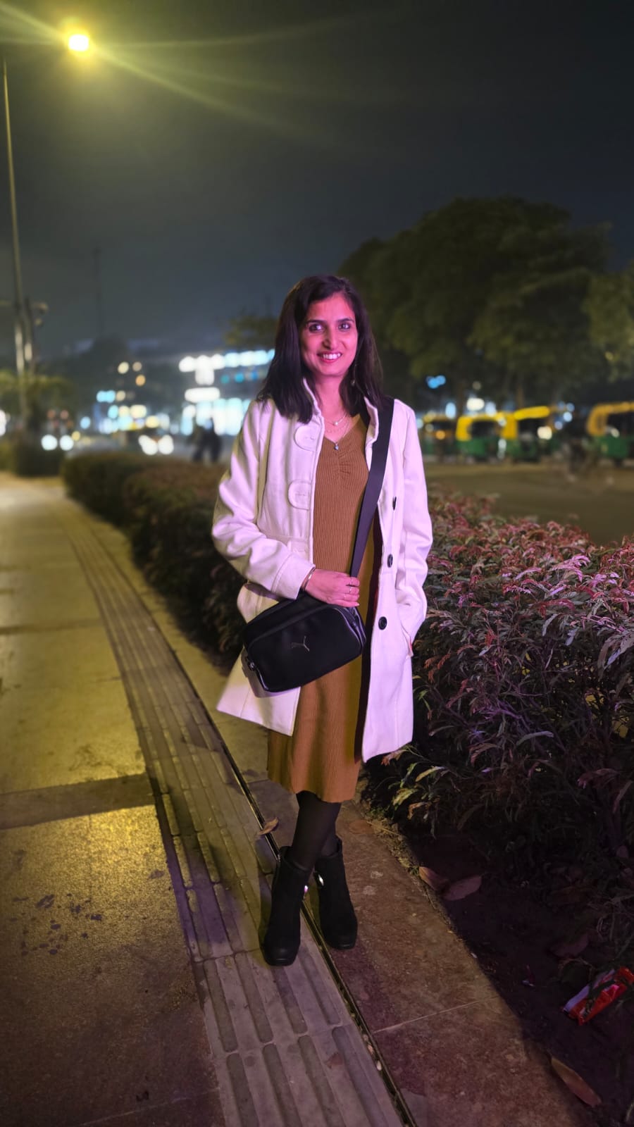 Street style — white trench coat, mustard midi dress, city lights at night