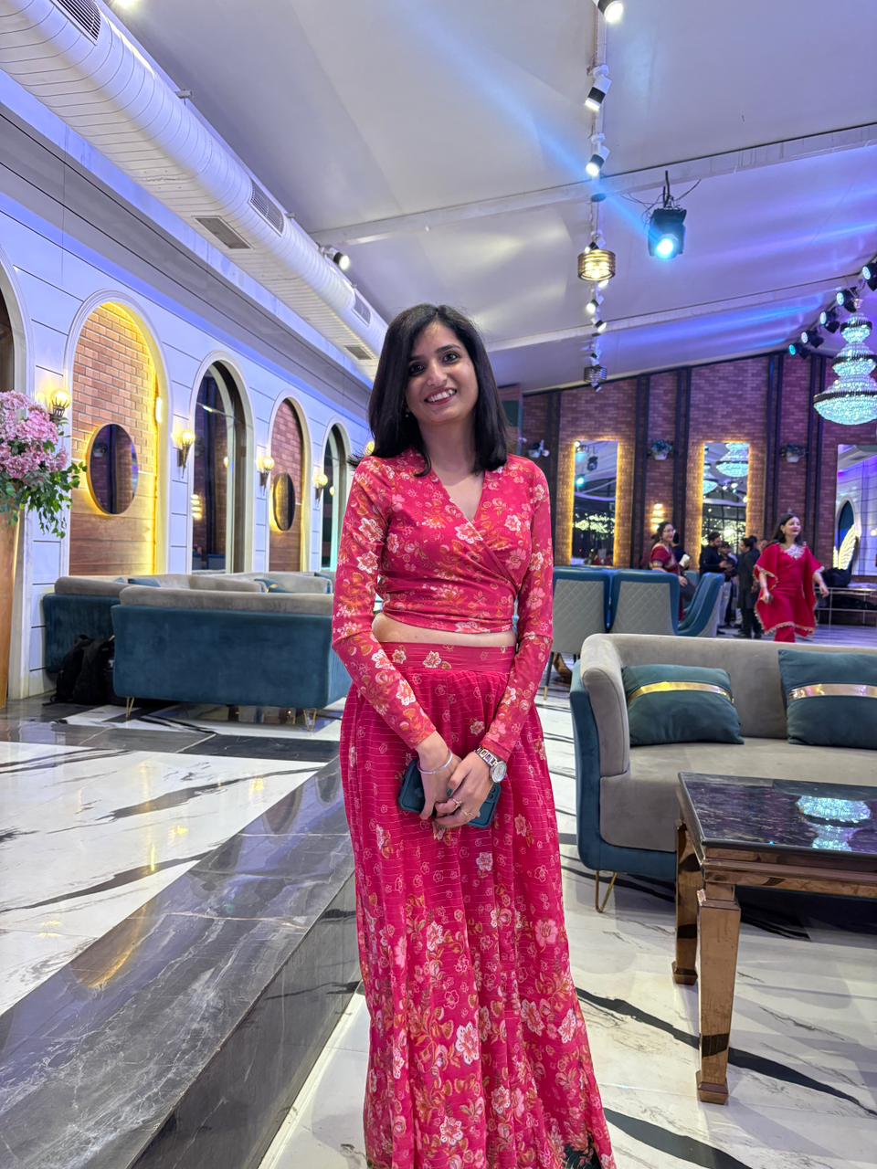 Festive occasion wear — vibrant red floral lehenga in a grand ballroom