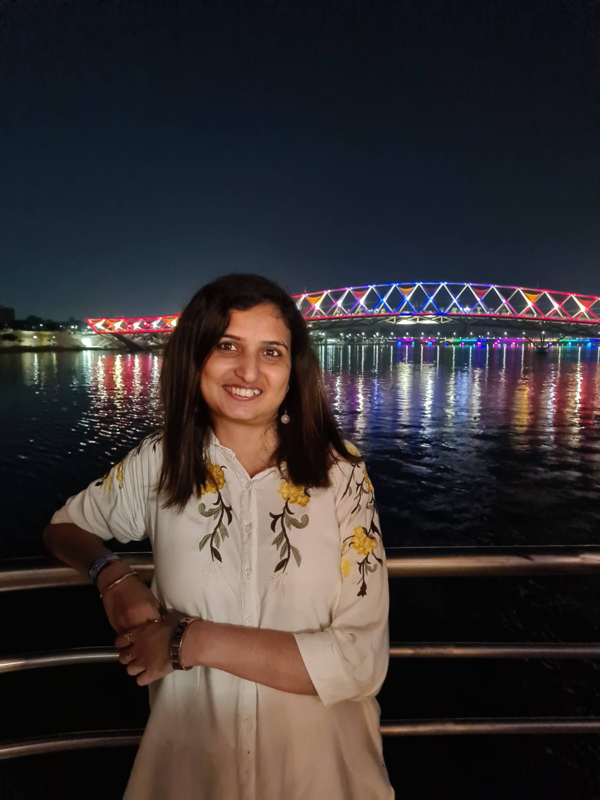 Casual night — white embroidered shirt, illuminated bridge reflected on river